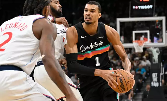 San Antonio Spurs center Victor Wembanyama (1) drives against Los Angeles Clippers' Derrick Jones Jr., second from right, and Kawhi Leonard (2) during the first half of an NBA basketball game, Friday, March 6, 2026, in San Antonio. (AP Photo/Darren Abate)