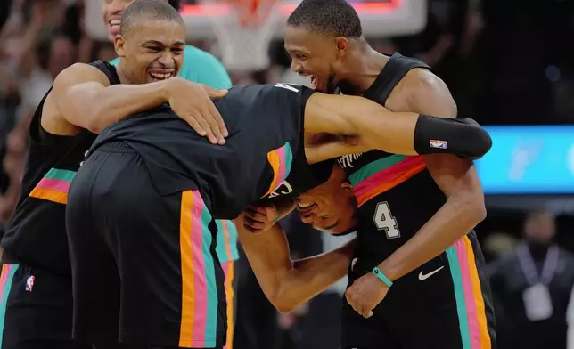 San Antonio Spurs players Victor Wembanyama, center, De'Aaron Fox (4) and Keldon Johnson celebrate their win after an NBA basketball game against the Los Angeles Clippers, Friday, March 6, 2026, in San Antonio. (AP Photo/Darren Abate)