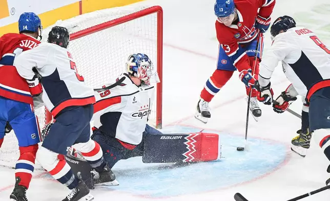 Montreal Canadiens' Cole Caufield (13) scores against Washington Capitals goaltender Charlie Lindgren (79) as Canadiens' Nick Suzuki (14) Capitals' Matt Roy (3) and Alex Ovechkin (8) look for a rebound during the first period of an NHL hockey game in Montreal, Saturday, Feb. 28, 2026. (Graham Hughes/The Canadian Press via AP)