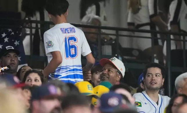 Former professional baseball player Manny Ramirez, second from right, greets a fan during the fifth inning of a World Baseball Classic game between the United States and Brazil, Friday, March 6, 2026, in Houston. (AP Photo/Ashley Landis)