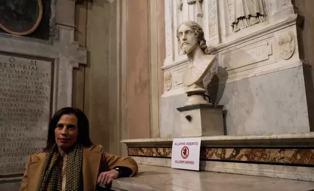 Italian researcher Valentina Salerno poses for photographers near the sculpted bust held inside the Basilica of Saint Agnes Outside the Walls, in Rome, Italy, Wednesday, March 4, 2026, which, in light of new studies, may be reattributed to Michelangelo Buonarroti. (AP Photo/Gregorio Borgia)