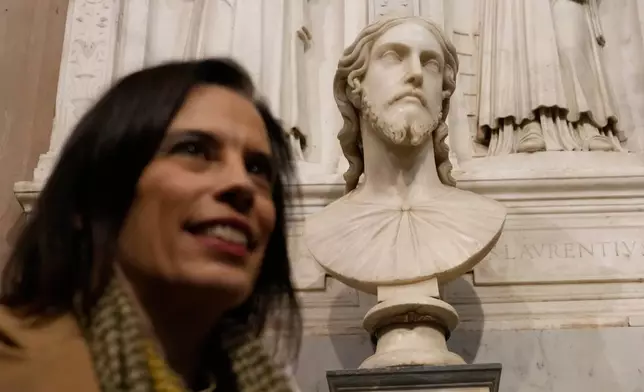 Italian researcher Valentina Salerno poses for photographers near the sculpted bust held inside the Basilica of Saint Agnes Outside the Walls, in Rome, Italy, Wednesday, March 4, 2026, which, in light of new studies, may be reattributed to Michelangelo Buonarroti. (AP Photo/Gregorio Borgia)