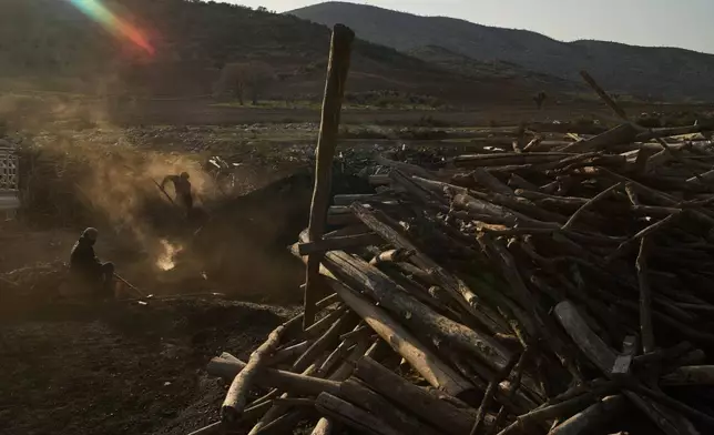 Men work at a traditional charcoal production site in Sarkand, Iraq, Thursday, March 12, 2026. (AP Photo/Leo Correa)