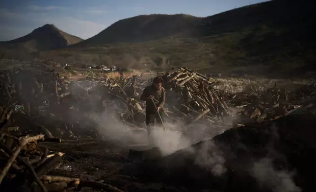 A man uses a shovel as he works at a traditional charcoal production site in Sarkand, Iraq, Thursday, March 12, 2026. (AP Photo/Leo Correa)