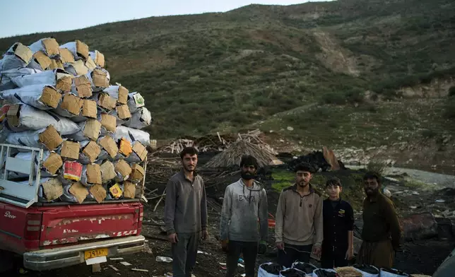 Workers and a boy pose for a photo after loading a vehicle with sacks of charcoal at a traditional production site in Sarkand, Iraq, Thursday, March 12, 2026. (AP Photo/Leo Correa)