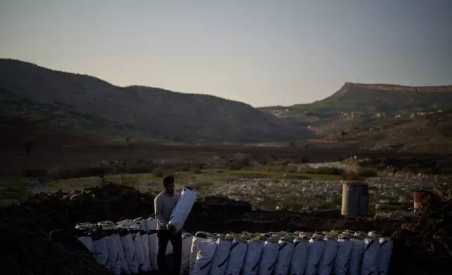 A worker carries a sack of charcoal at a traditional production site in Sarkand, Iraq, Thursday, March 12, 2026. (AP Photo/Leo Correa)
