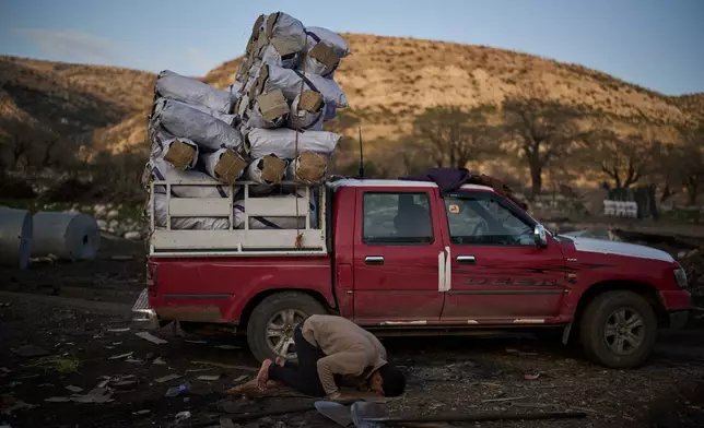 A Muslim worker prays next to a vehicle loaded with sacks of charcoal at a traditional production site in Sarkand, Iraq, Thursday, March 12, 2026. (AP Photo/Leo Correa)
