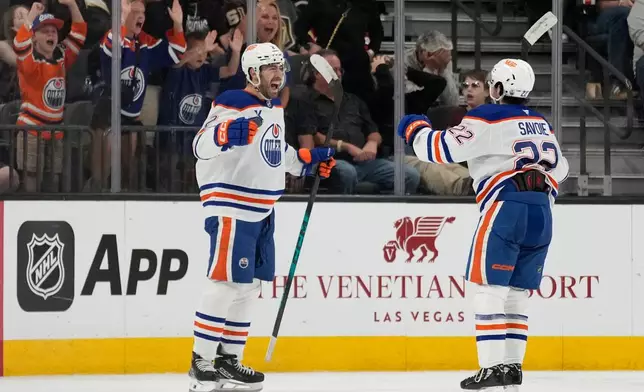 Edmonton Oilers defenseman Evan Bouchard, left, celebrates after scoring against the Vegas Golden Knights during overtime of an NHL hockey game Thursday, March 26, 2026, in Las Vegas. (AP Photo/John Locher)