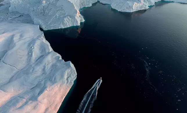 A fishing boat rides in front of an iceberg at Disko Bay near Ilulissat, Greenland, on Wednesday, Jan. 28, 2026. (AP Photo/Evgeniy Maloletka)