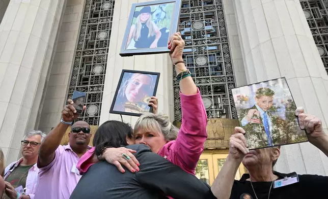 Lori Schott, center, is embraced as she holds up a photo of her daughter Annalee Schott, after the verdict in a landmark trial over whether social media platforms deliberately addict and harm children at Los Angeles Superior Court, Wednesday, March 25, 2026, in Los Angeles. (AP Photo/William Liang)