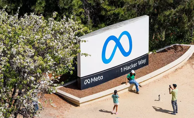 Visitors take photos at a sign outside Meta headquarters on Thursday, March 26, 2026, in Menlo Park, Calif. (AP Photo/Noah Berger)