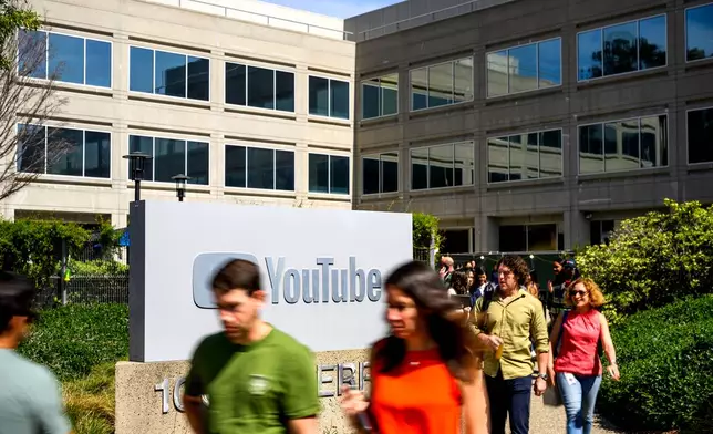 Workers pass a sign at YouTube headquarters on Thursday, March 26, 2026, in San Bruno, Calif. (AP Photo/Noah Berger)