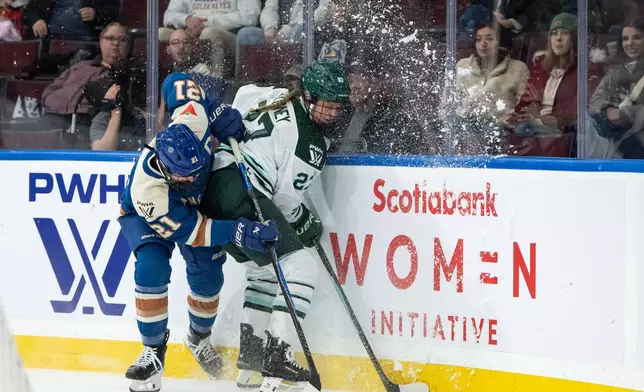 Vancouver Goldeneyes' Ashton Bell (21) and Boston Fleet's Shay Maloney (27) vie for the puck during the second period of a PWHL hockey game in Vancouver, British Columbia, Tuesday, March 10, 2026. (Ethan Cairns/The Canadian Press via AP)