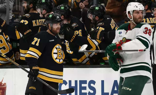 Boston Bruins' Viktor Arvidsson (71) is congratulated at the bench after scoring as Minnesota Wild's Ryan Hartman (38) skates past during the second period of an NHL hockey game Saturday, March 28, 2026, in Boston. (AP Photo/Winslow Townson)