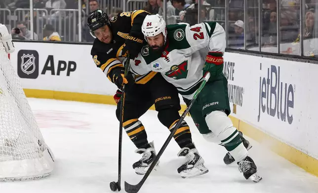 Minnesota Wild's Zach Bogosian tries to hold off Boston Bruins' David Pastrnak during the second period of an NHL hockey game Saturday, March 28, 2026, in Boston. (AP Photo/Winslow Townson)
