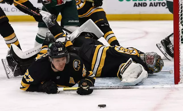Boston Bruins defenseman Hampus Lindholm (27) and goaltender Jeremy Swayman, right, watch the puck near the crease during the second period of an NHL hockey game against the Minnesota Wild, Saturday, March 28, 2026, in Boston. (AP Photo/Winslow Townson)