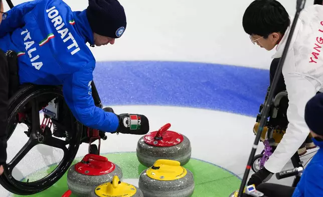 Paolo Ioriatti, left, of Italy, and Jinqiao Yang, right, of China, look at curling stones during a wheelchair curling mixed doubles at the 2026 Winter Paralympics, in Cortina d'Ampezzo, Italy, Thursday, March 5, 2026. (AP Photo/Evgeniy Maloletka)