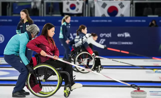 Polina Rozkova of Latvia, pushes a stone during a wheelchair curling mixed doubles round robin session against Great Britain at the 2026 Winter Paralympics, in Cortina d'Ampezzo, Italy, Thursday, March 5, 2026. (AP Photo/Evgeniy Maloletka)