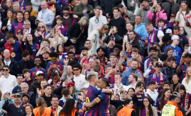 Barcelona's Raphinha, centre right, celebrates with Barcelona's Dani Olmo after scoring his side's fourth goal during the Spanish La Liga soccer match between Barcelona and Sevilla in Barcelona, Spain, Sunday, March 15, 2026. (AP Photo/Joan Monfort)