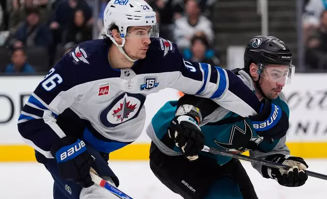 Winnipeg Jets center Morgan Barron (36) and San Jose Sharks defenseman Dmitry Orlov (9) chase after the puck during the second period of an NHL hockey game, Sunday, March 1, 2026, in San Jose, Calif. (AP Photo/Godofredo A. Vásquez)