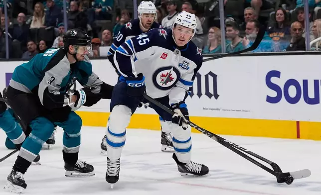 Winnipeg Jets left wing Cole Koepke (45) moves the puck while defended by San Jose Sharks defenseman John Klingberg (3) during the second period of an NHL hockey game, Sunday, March 1, 2026, in San Jose, Calif. (AP Photo/Godofredo A. Vásquez)