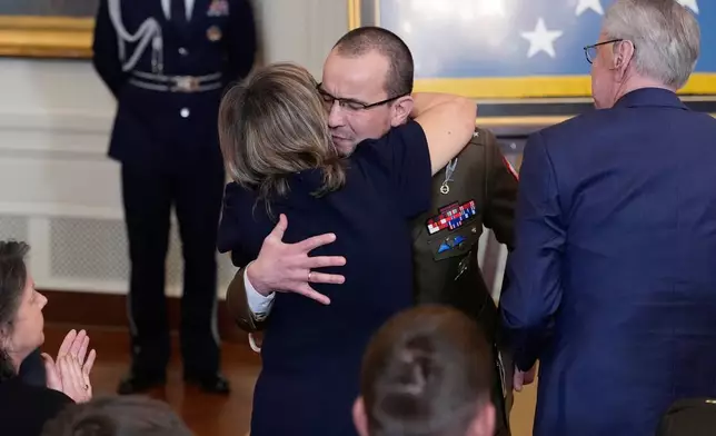 Polish Army Lt. Karol Cierpica, who was saved by Medal of Honor recipient Staff Sergeant Michael Ollis, embraces Ollis' parents Robert and Linda Ollis during a Medal of Honor ceremony at the White House, Monday, March 2, 2026, in Washington. (AP Photo/Alex Brandon)