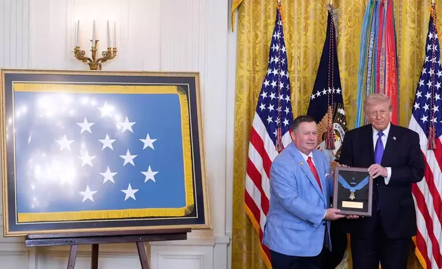 Chris Edmonds, left, son of Master Sergeant Roderick Edmonds, with President Donald Trump, is presented the Medal of Honor on behalf of his father, during a ceremony in the East Room of the White House, Monday, March 2, 2026, in Washington. (AP Photo/Alex Brandon)