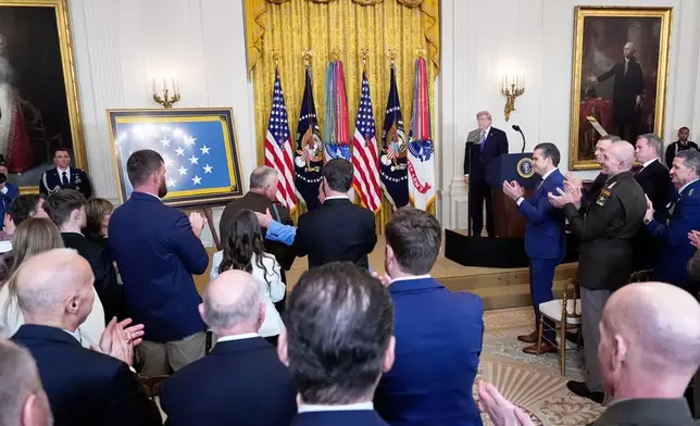 President Donald Trump looks on during a standing ovation for Sergeant Major Terry P. Richardson, U.S. Army (retired), center with hand on his back, during a Medal of Honor ceremony in the East Room of the White House, Monday, March 2, 2026, in Washington. (AP Photo/Alex Brandon)