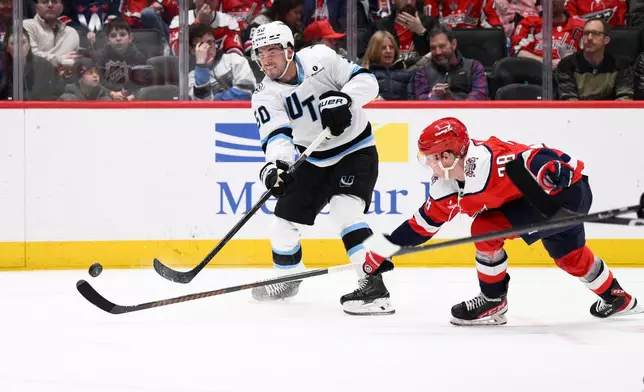 Utah Mammoth defenseman Sean Durzi (50) shoots the puck against Washington Capitals defenseman Rasmus Sandin (38) during the second period of an NHL hockey game, Tuesday, March 3, 2026, in Washington. (AP Photo/Nick Wass)