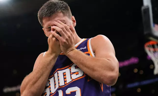 Phoenix Suns guard Collin Gillespie (12) reacts after getting hit in the face during the first half of an NBA basketball game against the Boston Celtics, Monday, March 16, 2026, in Boston. (AP Photo/Charles Krupa)