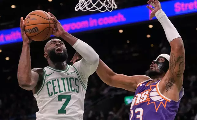 Boston Celtics guard Jaylen Brown (7) is fouled by Phoenix Suns guard Jordan Goodwin (23) on a drive to the basket during the first half of an NBA basketball game, Monday, March 16, 2026, in Boston. (AP Photo/Charles Krupa)