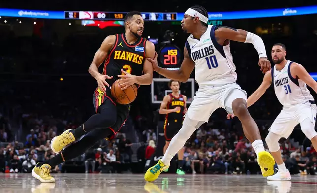 Atlanta Hawks guard CJ McCollum, left, drives to the basket against Dallas Mavericks guard Brandon Williams (10) during the first half of an NBA basketball game, Tuesday, March 10, 2026, in Atlanta. (AP Photo/Colin Hubbard)