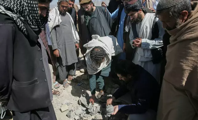 Residents and Taliban police gather the remains of a projectile at the site of a strike in Kabul, Afghanistan, Friday, March 13, 2026. (AP Photo/Barackatullah Popal)