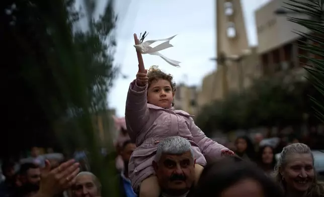 Catholic worshipers carry their children on their shoulders as they march in a procession during a Palm Sunday Mass in Beirut, Lebanon, Sunday, March 29, 2026. (AP Photo/Emilio Morenatti)