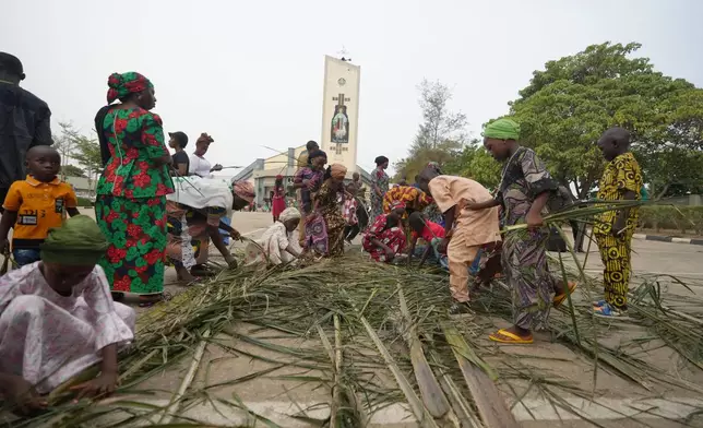 Catholic faithfuls collect palm fronds to commemorate Palm Sunday, outside St. Micheal's Cathedral church, in Minna, Nigeria, Sunday, March 29, 2026. (AP Photo/Sunday Alamba)