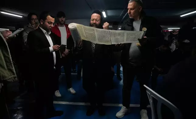 Jewish men read the Scroll of Esther as they celebrate the holiday of Purim in an underground parking garage as a precaution against possible Iranian missile attacks, in Tel Aviv, Israel, Monday, March 2, 2026. (AP Photo/Ohad Zwigenberg)