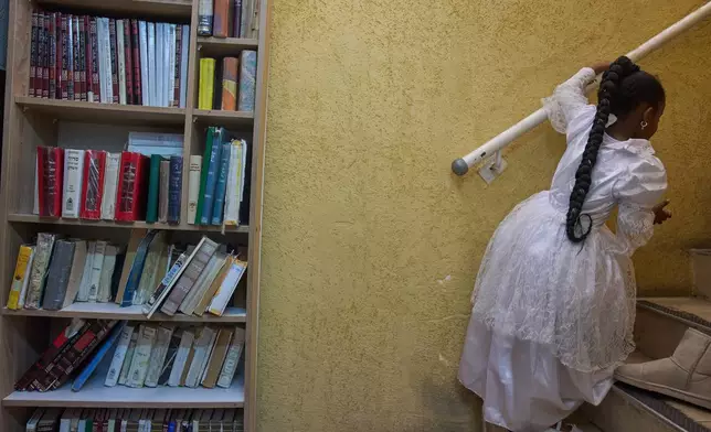 A girl wears a decorative dress during the Jewish festival of Purim inside a bomb shelter synagogue in Hadera, Israel, Monday, March 2, 2026. (AP Photo/Ariel Schalit)
