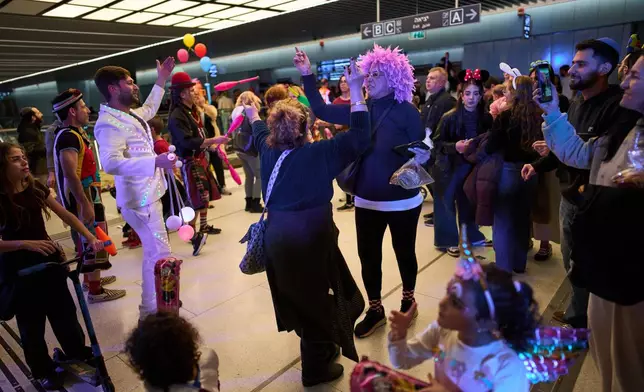 People, some wearing costumes, celebrate the Jewish holiday of Purim in an underground metro station used as a shelter against possible Iranian missile attacks, in Ramat Gan, Israel, Monday, March 2, 2026. (AP Photo/Oded Balilty)