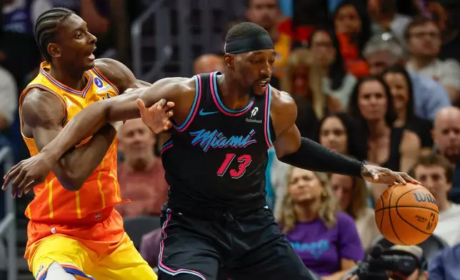 Miami Heat center Bam Adebayo (13) moves the ball against Charlotte Hornets forward Moussa Diabate, left, during the first half of an NBA basketball game in Charlotte, N.C., Friday, March 6, 2026. (AP Photo/Nell Redmond)