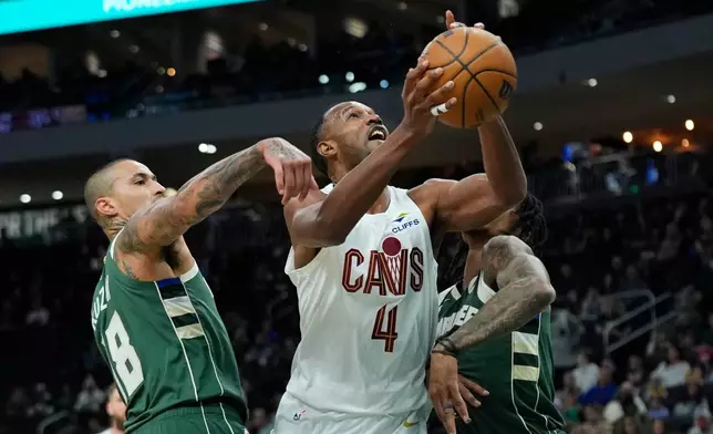 Cleveland Cavaliers' Evan Mobley (4) shoots between Milwaukee Bucks' Kyle Kuzma (18) and Kevin Porter Jr. during the first half of an NBA basketball game Tuesday, March 17, 2026, in Milwaukee. (AP Photo/Aaron Gash)