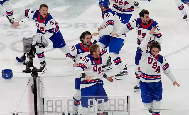 United States' Jack Hughes (86), right, celebrates with teammates after scoring the game winning goal against Canada in sudden death overtime during the men's ice hockey gold medal game at the 2026 Winter Olympics, in Milan, Italy, Sunday, Feb. 22, 2026. (AP Photo/Luca Bruno)