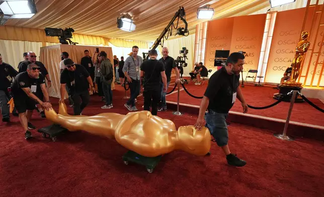 Workers install an Oscar statue at the Dolby Theatre in Los Angeles, Saturday, March 14, 2026, in preparation for Sunday's 98th Academy Awards ceremony. (AP Photo/Gregory Bull)