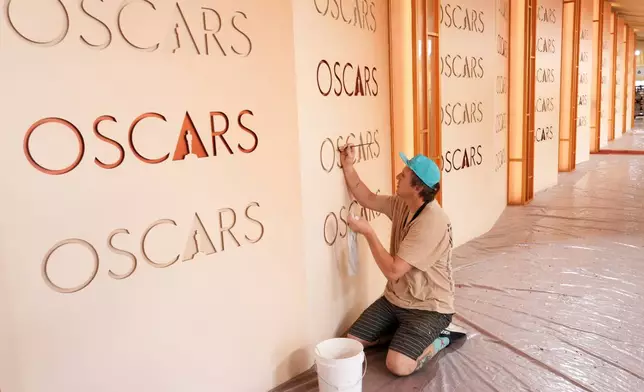 Motion picture painter Chance Gugler, whose father was also a film set painter who worked on over 80 movies, touches up an Oscars backdrop on Friday, March 13, 2026, at the Dolby Theatre in Los Angeles, in preparation for Sunday's Academy Awards ceremony. (AP Photo/Chris Pizzello)