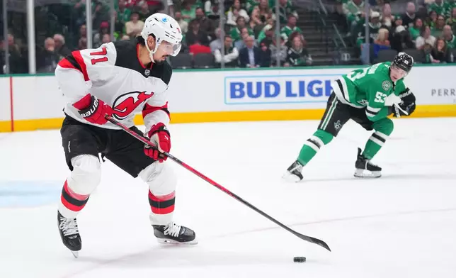New Jersey Devils defenseman Jonas Siegenthaler (71) skates with the puck as Dallas Stars center Wyatt Johnston (53) looks on during the first period of an NHL hockey game Tuesday, March 24, 2026, in Dallas. (AP Photo/Julio Cortez)