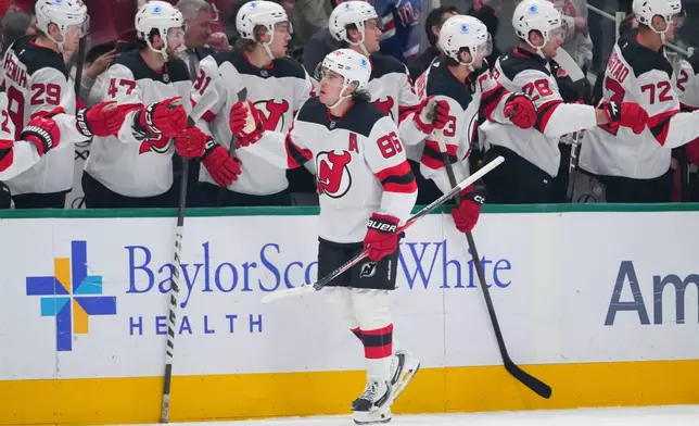 New Jersey Devils center Jack Hughes skates by his bench after scoring his first of two first period goals against the Dallas Stars during an NHL hockey game Tuesday, March 24, 2026, in Dallas. (AP Photo/Julio Cortez)