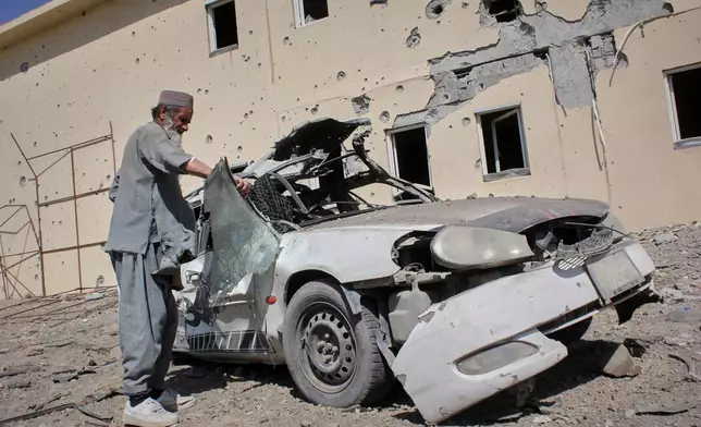A man inspects a car damaged after a Pakistani strike in on a refugee camp in Takhta Pul district, Kandahar province, Afghanistan, Saturday, Feb. 28, 2026. (AP Photo/Sibghatullah)