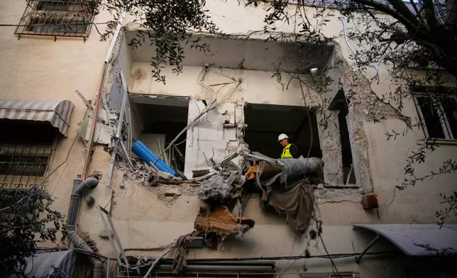 Israeli security forces inspect a damaged apartment building struck by an Iranian missile in Tel Aviv, Israel, Sunday, March 8, 2026. (AP Photo/Ohad Zwigenberg)