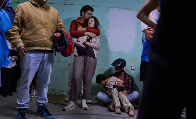 People take shelter as air raid sirens warning of incoming Iranian missiles in Tel Aviv, Israel, Saturday, March 7, 2026. (AP Photo/Oded Balilty)