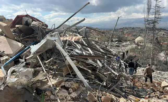 People check the damage left by Israeli airstrikes late Friday, in the village of Nabi Chit, eastern Lebanon, Saturday, March 7, 2026, where Israeli forces landed overnight and dug a grave in a cemetery searching for Israeli co-pilot Ron Arad who was captured and then went missing after his fighter jet crashed over south Lebanon in 1986. (AP Photo/Ali Salem)
