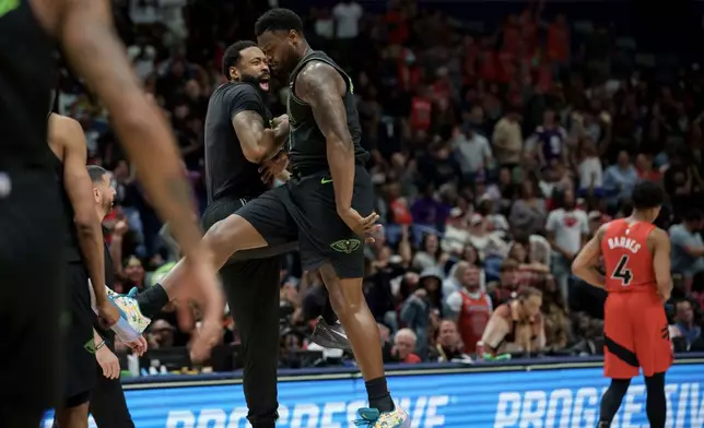 New Orleans Pelicans forward Zion Williamson, center, celebrates a windmill dunk against the Toronto Raptors with center DeAndre Jordan next to Toronto Raptors forward Scottie Barnes (4) during the second half of an NBA basketball game in New Orleans, Wednesday, March 11, 2026. (AP Photo/Matthew Hinton)